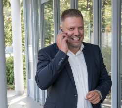 Ein Mann im Anzug telefoniert lächelnd im Freien.