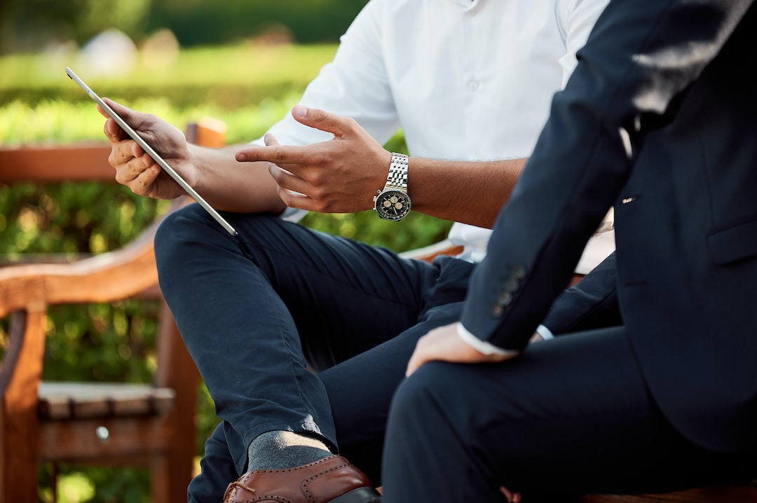 Zwei Personen sitzen im Freien und diskutieren über einen Tablet-Computer.